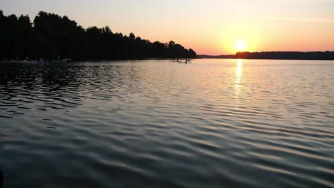 Paddle boarder drifting on tranquil lake at sunset. Silhouette of person Stock Footage 340356851