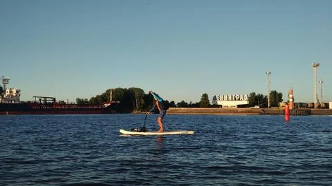 A paddle boarder sails on a sup board in the port of St. Petersburg. Stock Photos