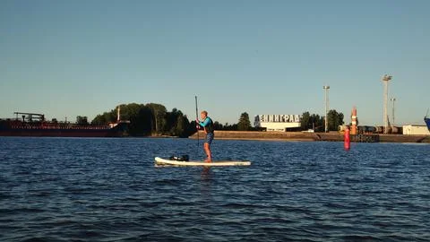 A paddle boarder sails on a sup board in the port of St. Petersburg. Stock Photos