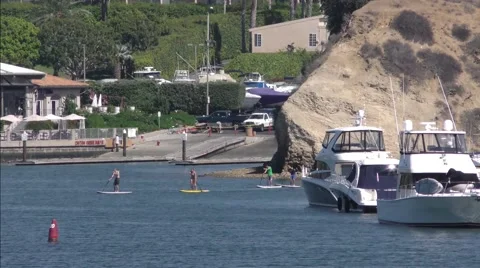 Paddle boarders long shot by cliff with boat launch ramp and marina.mp4 Stock Footage 67549778