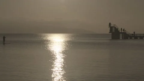 Paddle-boarders paddle into frame during Irish Winter Afternoon Sun Stock Footage 149845841