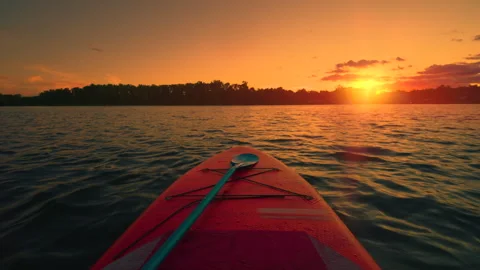 Paddleboard POV View at Sunset on River | Orange Sky over Calm Water | SUP Board Stock Footage 344829849
