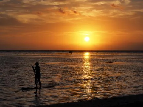 Paddleboarding during sunset in the lagoon of Ermitage - Reunion Island Stock Photos