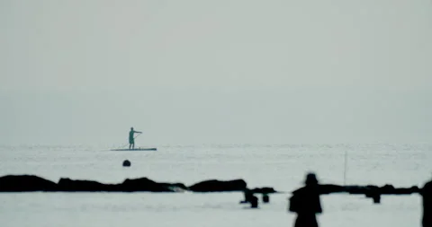 Paddleboarding in Harmony with the Rhythmic Dance of the Ocean's Breath Stock Footage 254561084