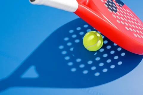 Padel ball in midair with racket shadow pattern on blue court background 库存照片