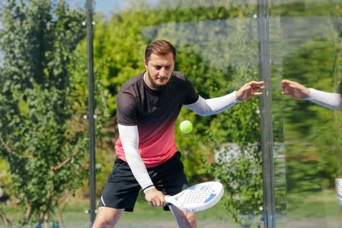 Padel Player Practicing a Wall Shot on an Outdoor Glass Court Stock Photos