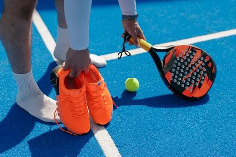 Padel player preparing for training with racket, ball, and court shoes Stock Photos
