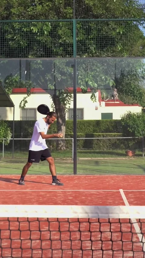 Padel player taking a serve after bouncing ball several times on a court. Stock Footage 312275392