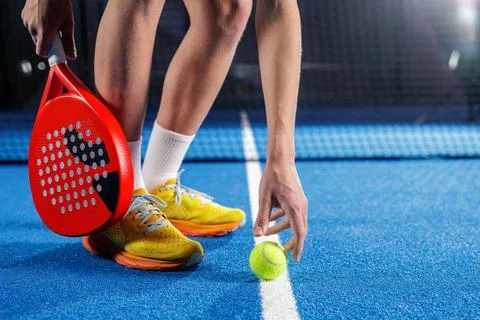 Padel serve setup with player placing ball on line on indoor blue court Stock Photos