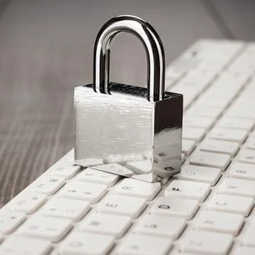 Padlock and white computer keyboard on the wooden office table Stock Photos