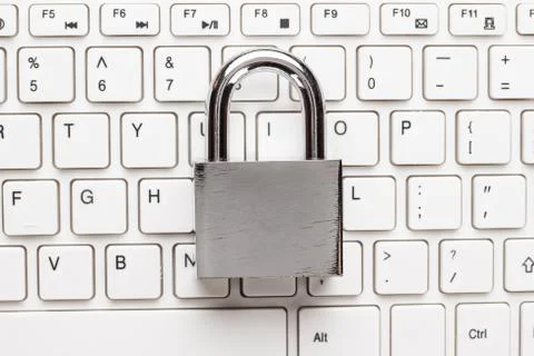 Padlock and white computer keyboard on the wooden office table Stock Photos