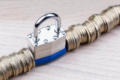Padlock between a row of coins Foto stock