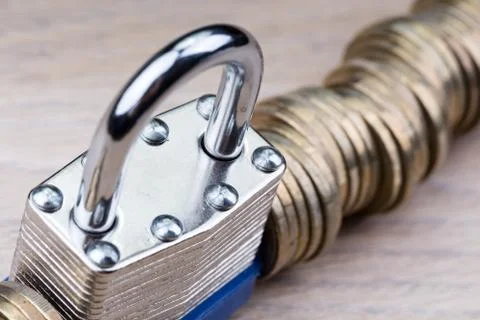 Padlock between a row of coins Foto stock