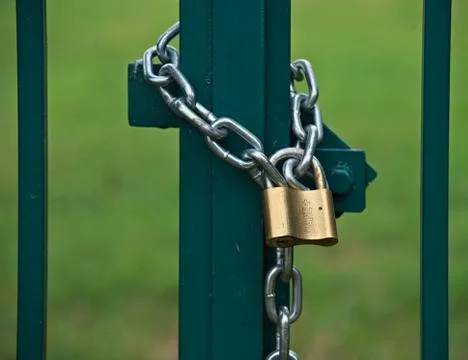 Padlock with chain locking gate on a field Stock Photos