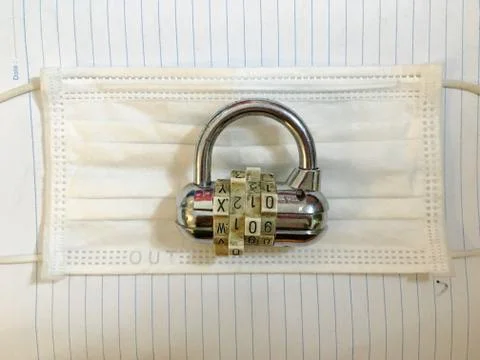 Padlock combination lock on white surgical medical masks for lockdown like Stock Photos