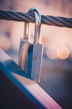 Padlock hanging on a wire on a bridge at sunset Stock Photos
