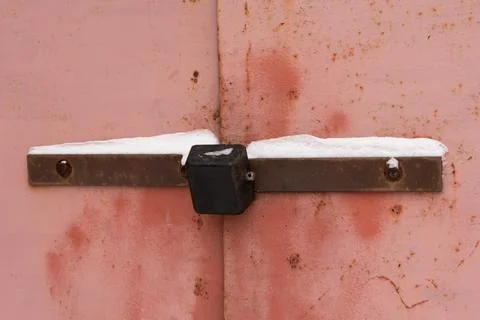 Padlock on an old iron gate with peeling paint and traces of rust Stock Photos