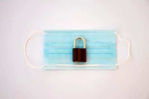 Padlock on a surgical mask representing a lockdown due to coronavirus crisis Stock Photos