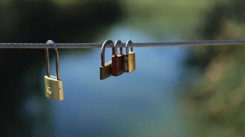 Padlocks Hanging on a Cable on the Background of a Pond. Slow Motions. 4K Stock Footage 287588436