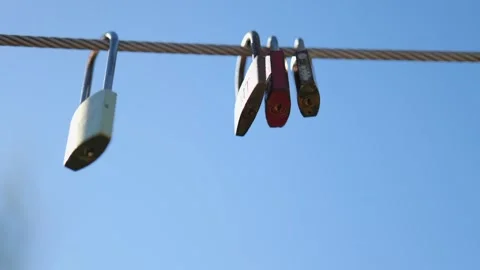 Padlocks Hanging on a Cable on a Blue Sky Background. Slow Motions. 4K Stock Footage 287588466