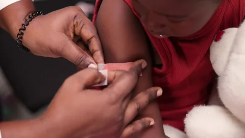 Paediatric hands applying plaster on African child in clinic during vaccination Stock Footage 346730928