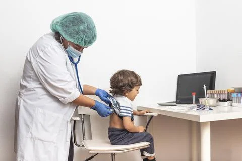 Paediatrician auscultates the back while checking the pneumonia of a blond Stock Photos
