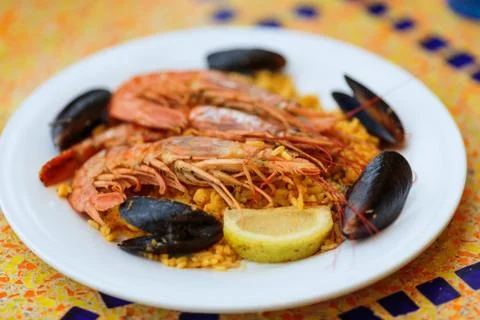 Paella portion, rice with tiger shrimps, mussels and lemon Stock Photos