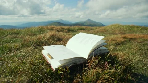 The pages of the book are blown by the wind. The book is in the mountains Stock Footage 218439067