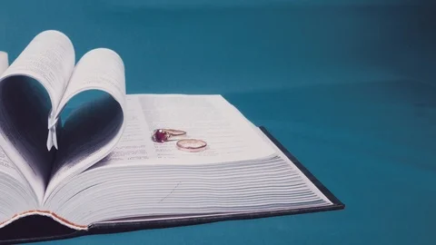 Pages of the book are folded in the form of a heart with wedding rings Stock Footage 101343043