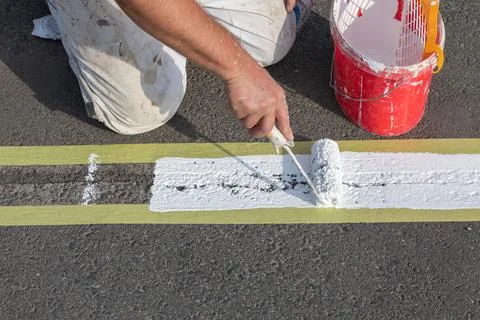 Paint is applied to the road using a paint roller. Stock Photos
