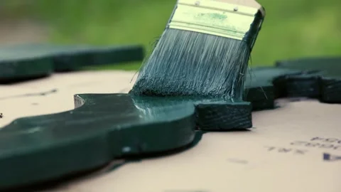 Paint brush close up while applying green color on wood ornament Stock Footage 247053963