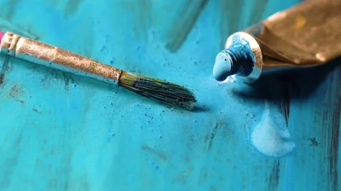 Paint brush on surface. Turquoise acrylic on canvas. Open colored tube on floor Stock Footage 150576290