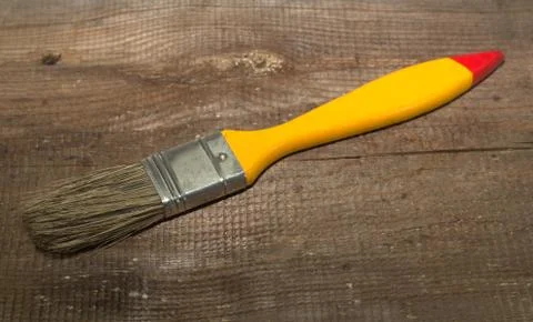 Paint brush width 1 inch with yellow handle on a wooden background Stock Photos