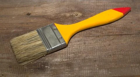 Paint brush width 2 inch with yellow handle on a wooden background Stock Photos