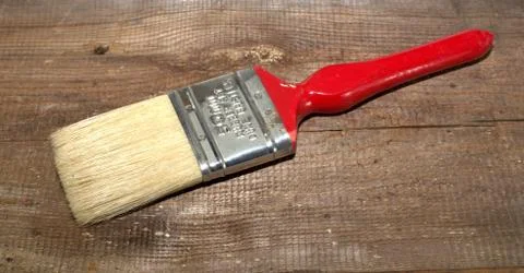 Paint brush width 2 inch with a red handle on a wooden background Stock Photos