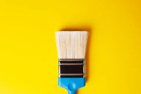 Paint brush on a yellow background, centered, repair concept. Stock Photos