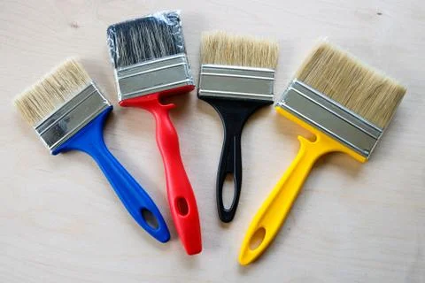 Paint brushes of different sizes and colos on a wooden surface Stock Photos