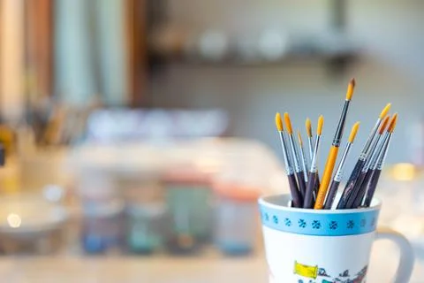 Paint brushes of different sizes in glasses, art background concept Stock Photos