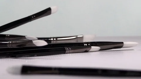Paint Brushes falling and bouncing off White Background in Slow Motion Stock Footage 129931006