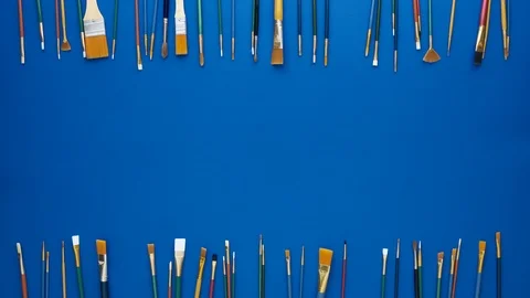 Paint brushes as frame. Flat lay shot, blue background. 4k loop 스톡 동영상 125714502