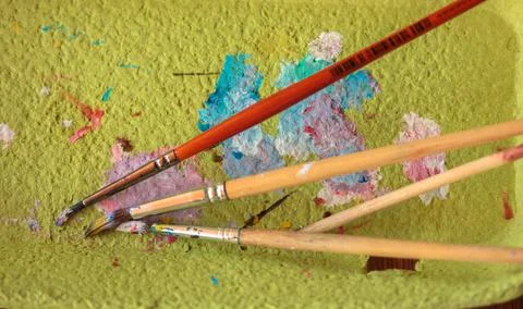 Paint brushes on green background flatly. Multicolored paints on paper. Drawing Stock Photos