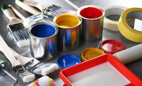 Paint cans and paintbrushes of different size for home decorating purposes... Stock Photos