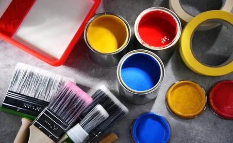 Paint cans and paintbrushes of different size for home decorating purposes... Stock Photos