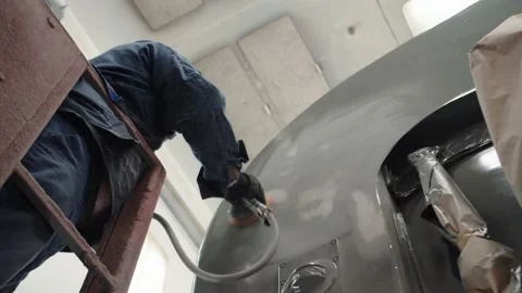 Paint dust flies from a pneumatic grinder, a worker in overalls and a respirator Stock Footage 196357197