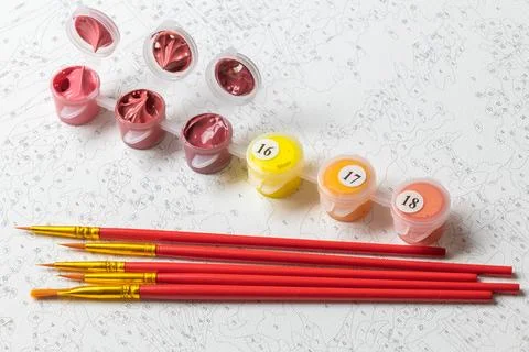 A paint-by-numbers canvas with numbered sections, red-handled paintbrushes, a Stock Photos