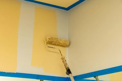 Paint roller adding fresh coat of paint to wall Stock Photos