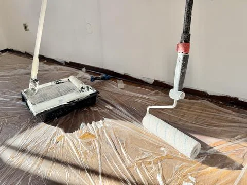 Paint Roller and White Paint Bucket on Protected Floor. Stock Photos