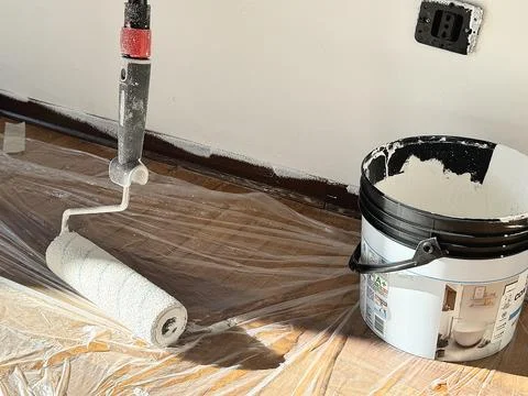 Paint Roller and White Paint Bucket on Floor. Stock Photos