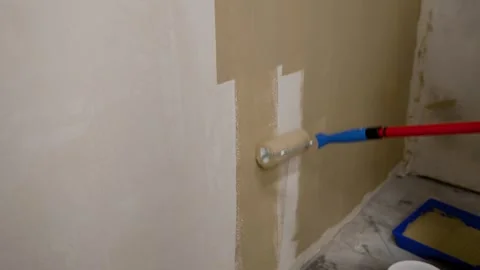 Paint roller applying beige paint to wall under exposed ceiling grid Stock Footage 338384772