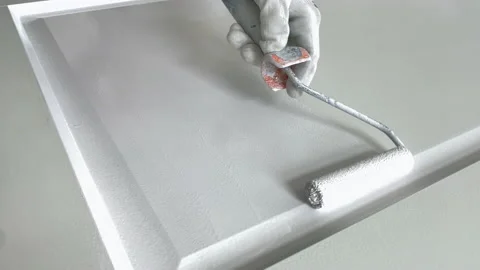 Paint roller closeup. Painter at work paints the wooden door with white paint Stockbeeldmateriaal 156661436